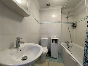 Et badeværelse med håndvask, toilet og badekar.