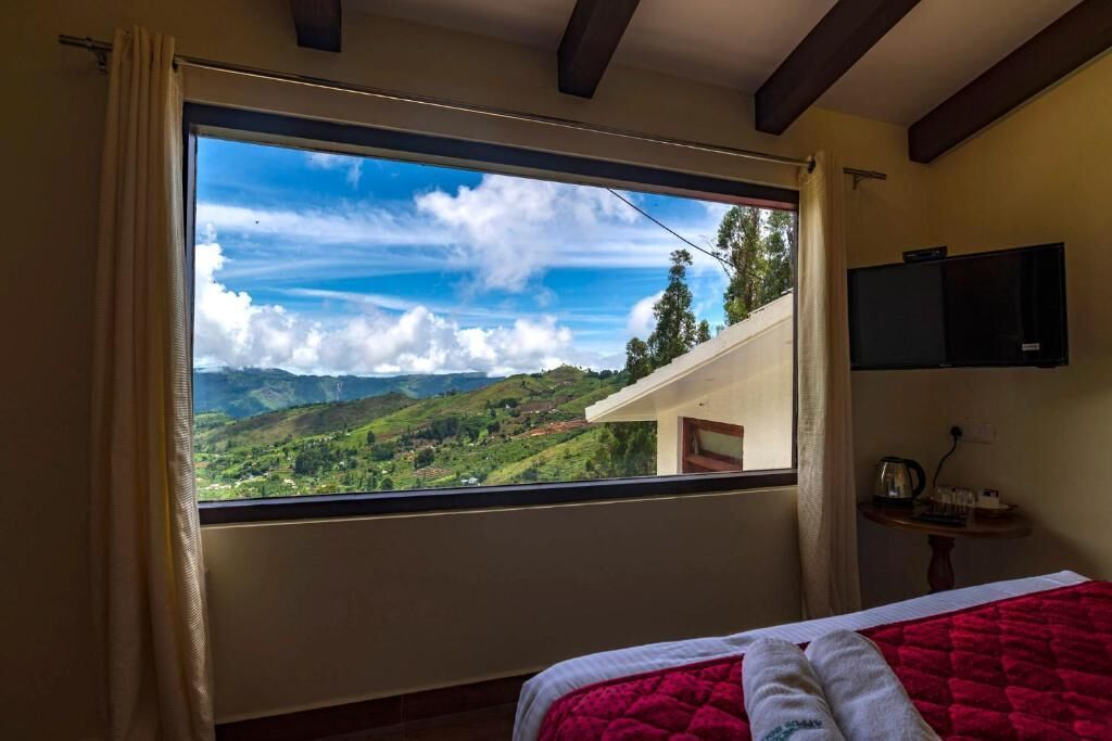 Ein Schlafzimmer mit großem Fenster, einem Bett, einem Fernseher und einem kleinen Tisch mit Wasserkocher.