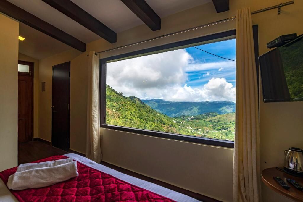 A room with a large window offering a view of a mountainous landscape.
