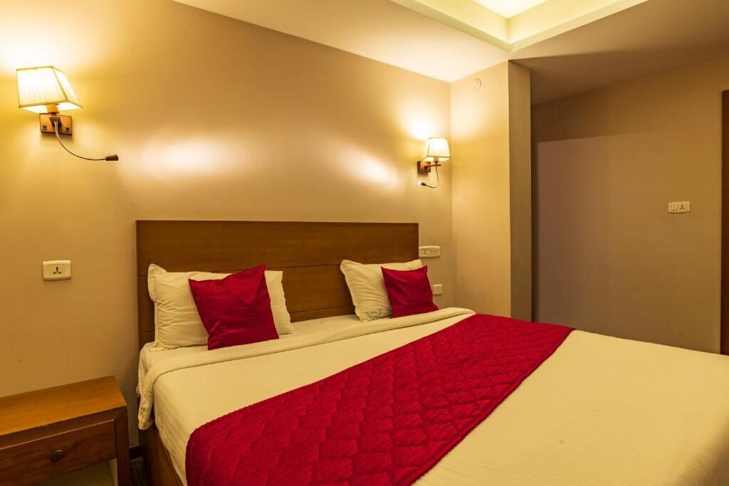 A hotel room with a bed, two wall-mounted lamps, a wooden headboard, and a nightstand.