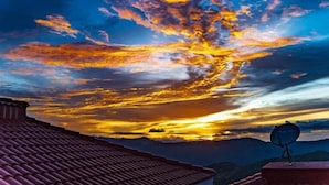 Un atardecer con una antena parabólica en un edificio.
