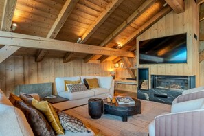 A cozy wooden interior with a sofa, a fireplace, and a television.