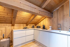 A compact kitchen with white cabinets, a wooden ceiling, and a small countertop. - Stunning 5-bedroom chalet in Mont d'Arbois (Megève)