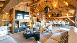 A spacious loft-style room with a fireplace, modern seating, and a dining area. - Stunning 5-bedroom chalet in Mont d'Arbois (Megève)