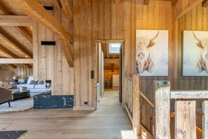 A wooden interior with a sofa, a black coffee table, and a hallway leading to a room with a door.