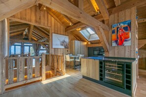 A rustic interior with wooden beams, a dining area, and a kitchen with a large island.