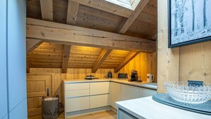 A kitchen with wooden beams, white cabinets, a coffee maker, and a glass bowl on the counter. - Stunning 5-bedroom chalet in Mont d'Arbois (Megève)