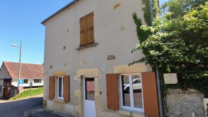 Un bâtiment à la façade en pierre, avec des volets en bois, et un ciel dégagé.