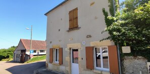 Un bâtiment à la façade en pierre, avec des volets en bois, et un ciel dégagé.