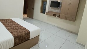 Un dormitorio con una cama, un ventilador de techo, un televisor montado en la pared y un armario.