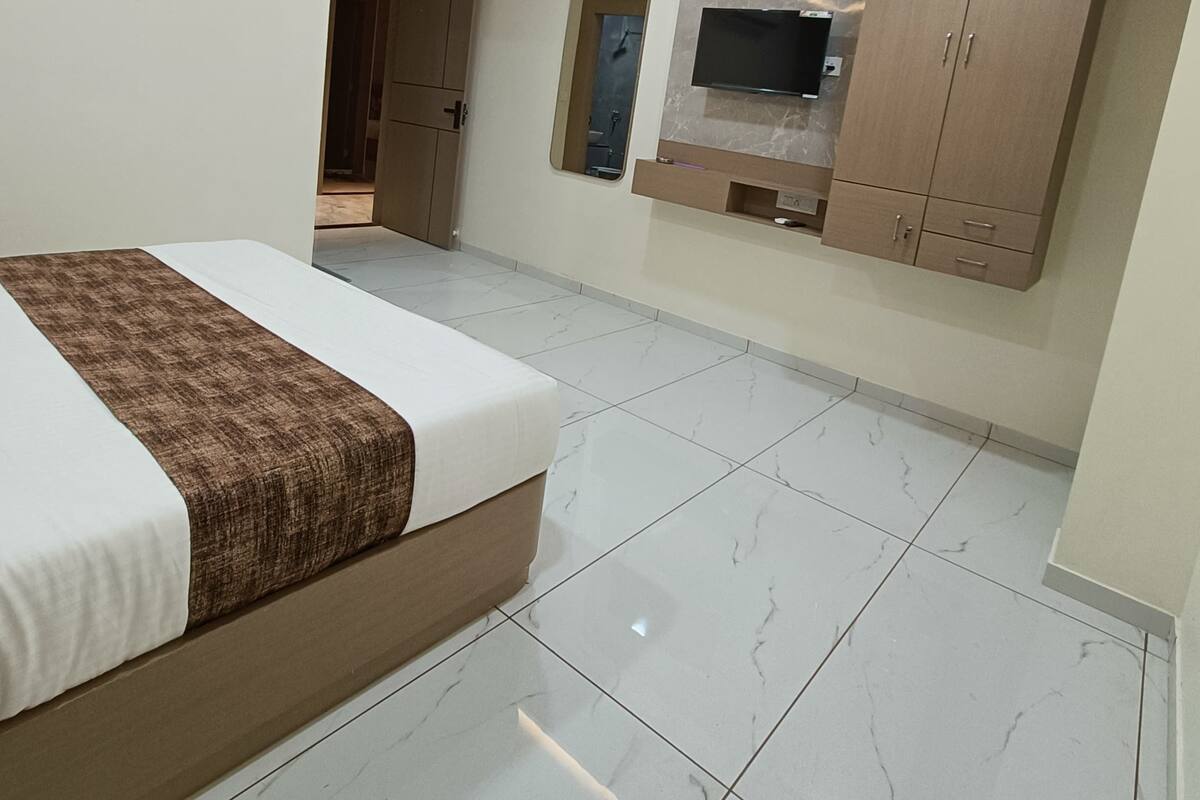 Un dormitorio con una cama, un ventilador de techo, un televisor montado en la pared y un armario.