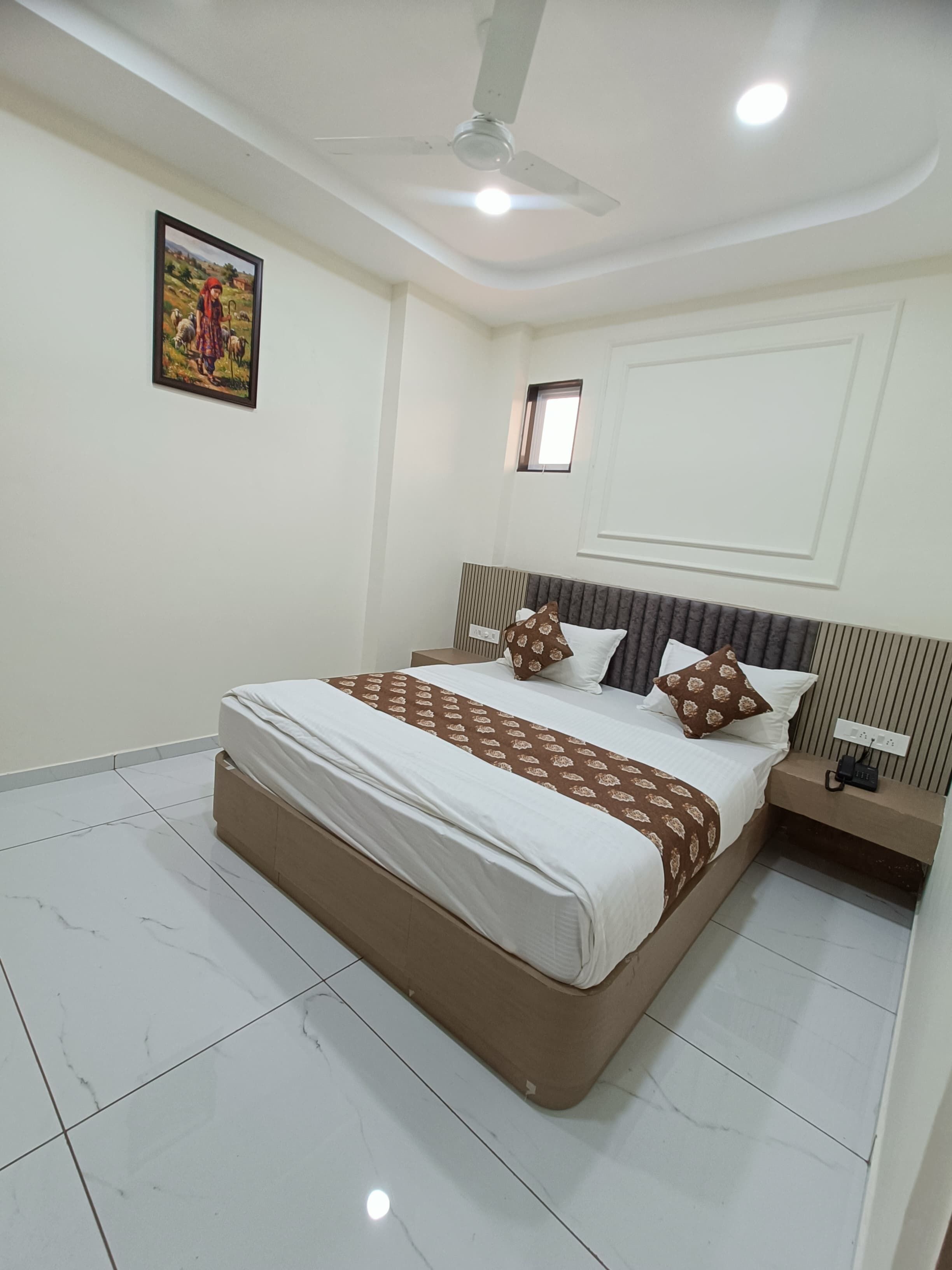 Een slaapkamer met een bed, nachtkastje, plafondventilator en een schilderij aan de muur.