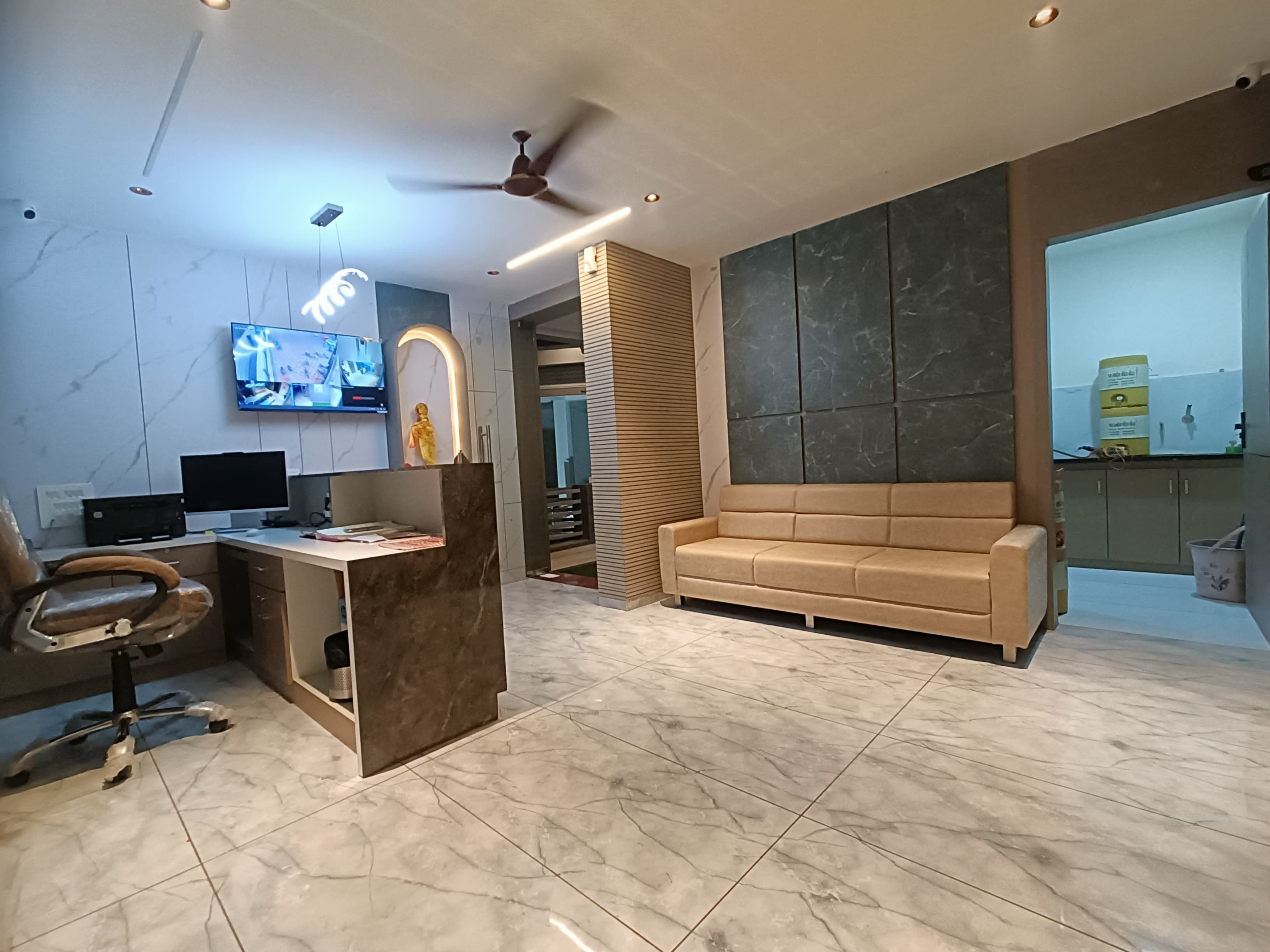 Una sala de estar moderna con un sofá, un escritorio con una computadora, un televisor y un ventilador de techo.