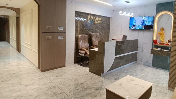 Un área de recepción con piso de mármol, un mostrador de recepción, una silla, un televisor y un ventilador de techo.
