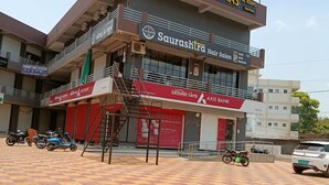 Un hotel llamado 'Hotel Radhe Raas' con un letrero de 'Saurashtra Hair Salon' y 'Axis Bank' en la planta baja.
