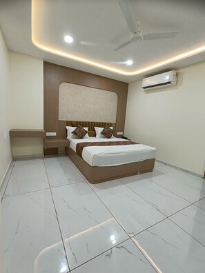Une chambre à coucher comprenant un lit, une table de chevet, un ventilateur de plafond et un appareil de climatisation.