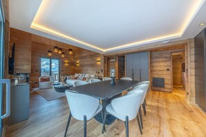 Ein modernes Interieur mit Holzboden, einem zentralen Esstisch und einer Sofagarnitur.