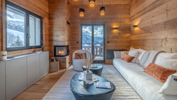 A log cabin interior with a fireplace, sofa, and dining area. - Luxury apartment—sleeps 10—near downtown (Megève)