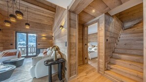 A wooden cabin interior with a sofa, a table, a bed, and a staircase. - Luxury apartment—sleeps 10—near downtown (Megève)
