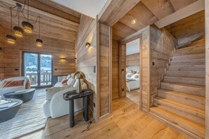Ein Holzblockhaus mit einer Couch, einem Tisch, einem Bett und einer Treppe.