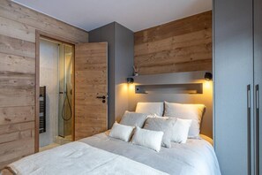 Ein Schlafzimmer mit Holzschrank, einem Bett mit vielen Kissen und einer Wandleuchte.