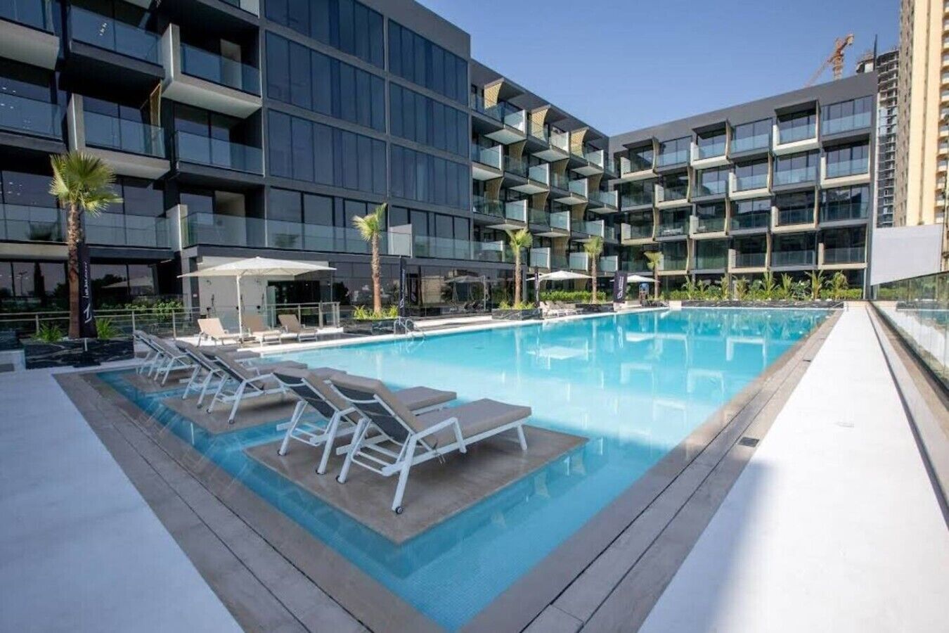 Ein modernes Hotel mit Pool auf dem Dach, mehreren Balkonen und Außenbereichen zum Sitzen.