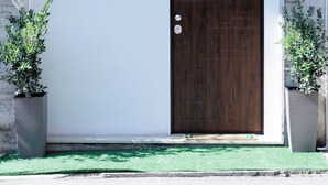 Un bâtiment doté d’une grande porte, d’une fenêtre au-dessus de la porte et de deux plantes en pot de chaque côté.