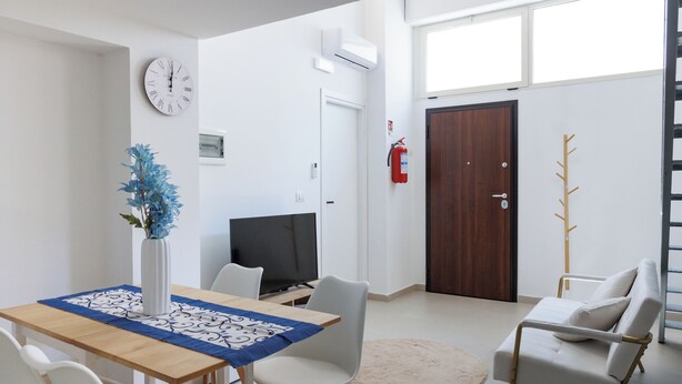 Un salon moderne comprenant une table à manger, des chaises, un téléviseur, un porte-manteau et une porte.