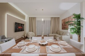 A dining area with a table set for six, a sofa, a TV, and a plant. - FIRST CLASS | 2BR | Relax & Unwind | Creek Beach (Dubai Creek Harbour)