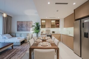 A modern kitchen with a dining area, a sofa, and a plant. - FIRST CLASS | 2BR | Relax & Unwind | Creek Beach (Dubai Creek Harbour)