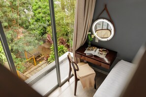 A room with a large window, a wooden desk, a chair, a bed, and a round mirror on the wall. - HAKU Boutique Hotel Da Lat - Ly Tu Trong (Xuan Huong - Da Lat)