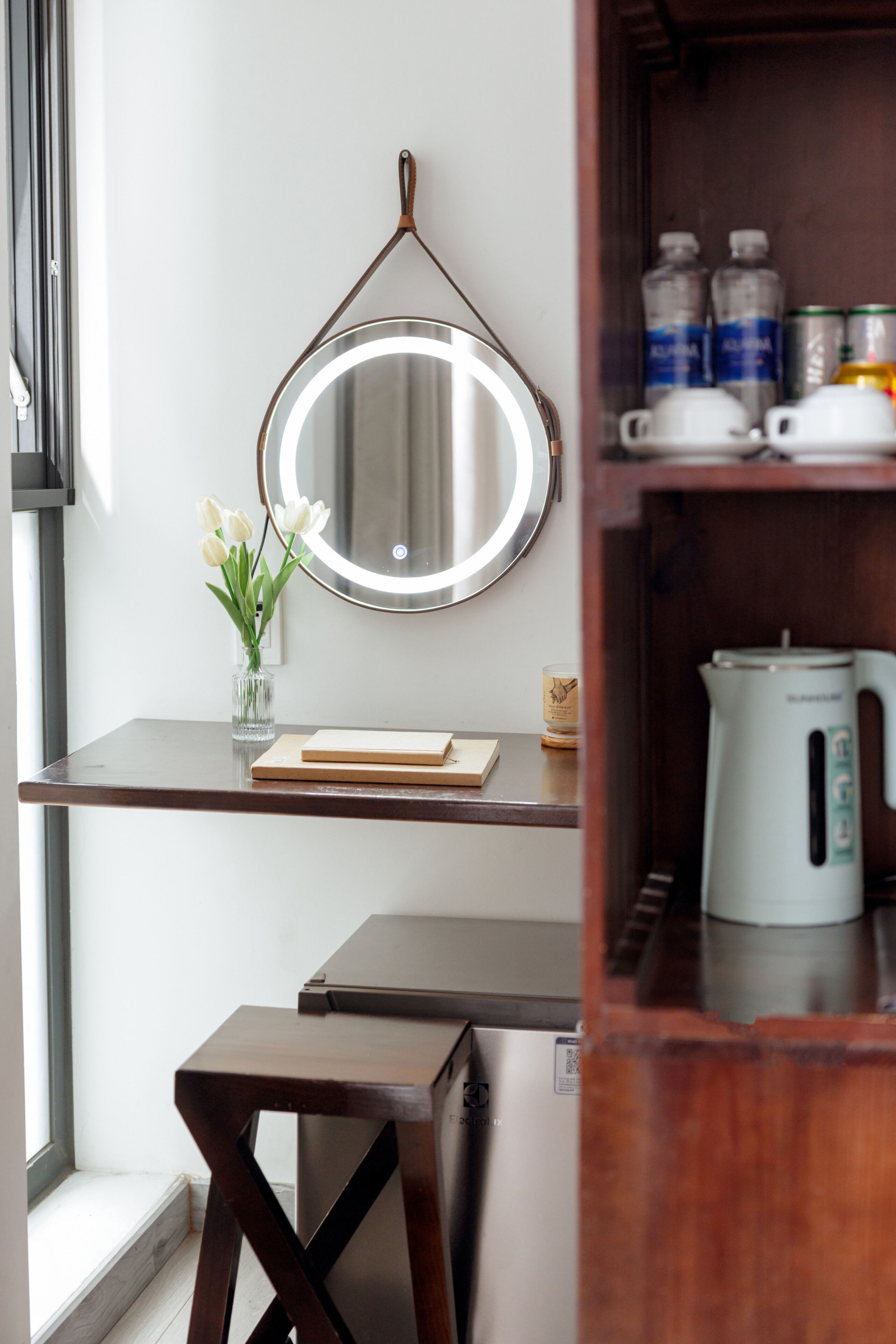 A modern kitchenette with a built-in stove, a coffee maker, and a shelf with kitchen essentials.