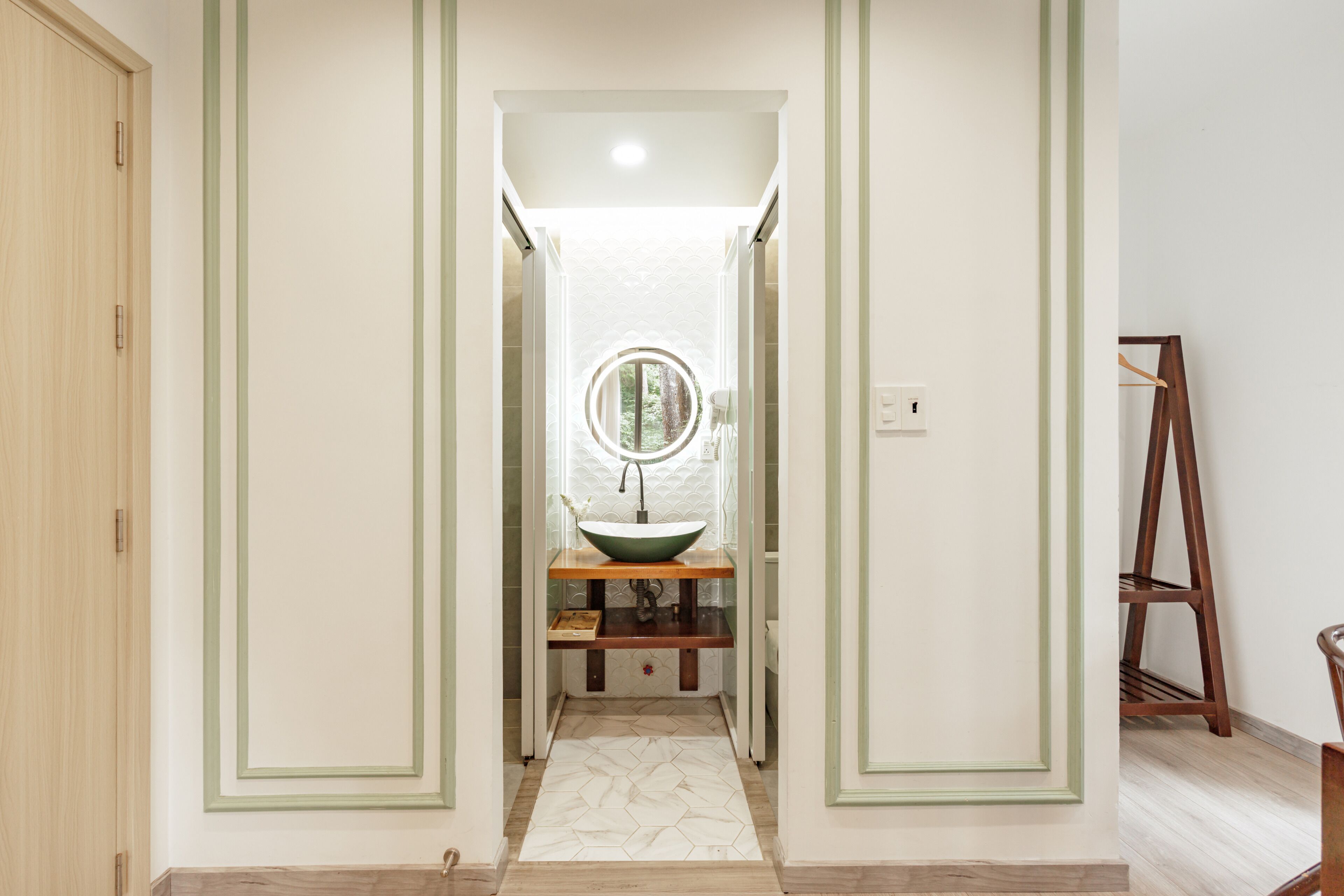 A hallway with a wooden door, a green-framed mirror, a wooden bench, and a wooden ladder.