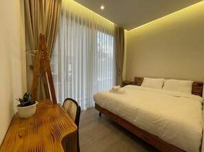 A hotel room with a bed, a wooden table with a plant, and a window with curtains. - HAKU Boutique Hotel Da Lat - Ly Tu Trong (Da Lat)