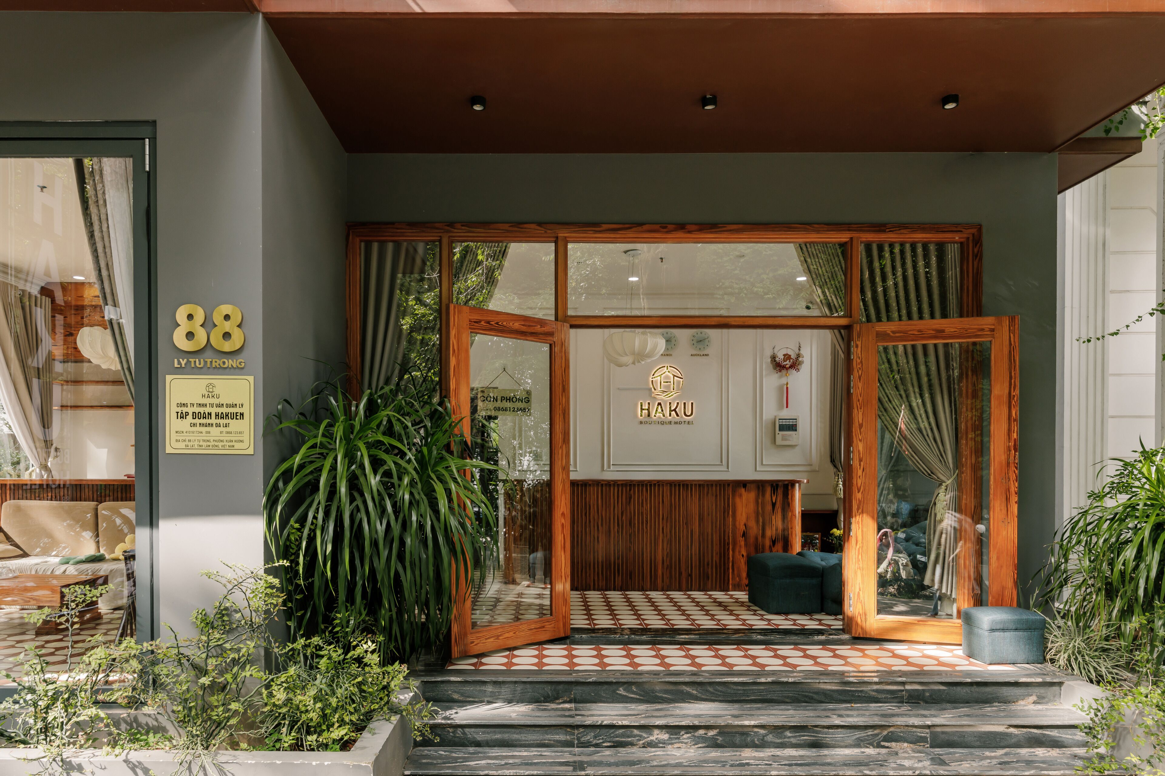 A hotel entrance with a number '88' sign, a wooden frame, and a signboard with 'HAKU BOUTIQUE HOTEL' written on it.