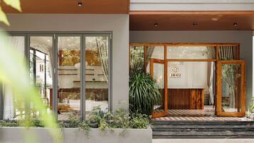 A hotel entrance with a wooden reception desk, a glass door, and a sign reading 'HAKU BOUTIQUE HOTEL'.