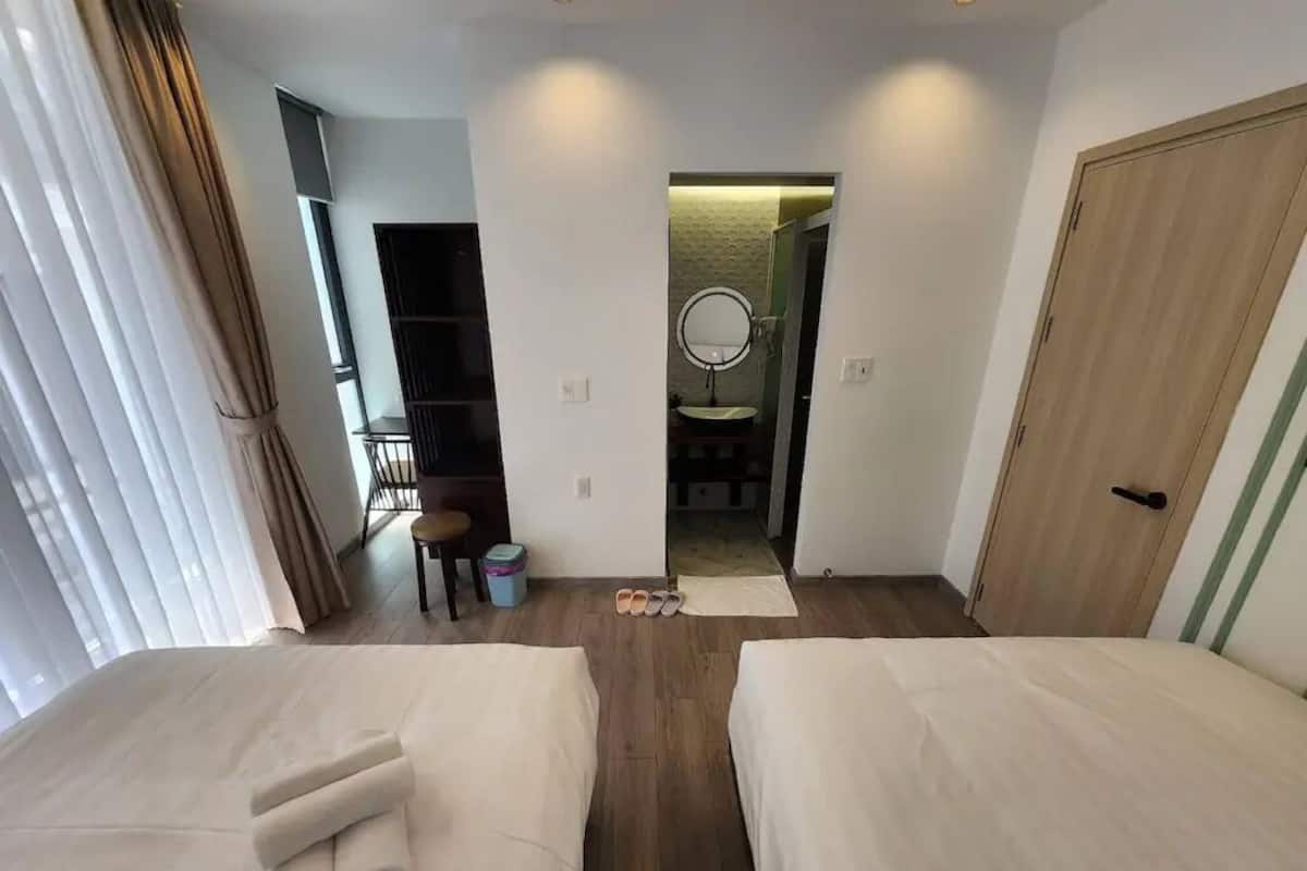A hotel room with two beds, a bathroom with a mirror, and a door leading to another room.