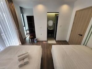 A hotel room with two beds, a bathroom with a mirror, and a door leading to another room. - HAKU Boutique Hotel Da Lat - Ly Tu Trong (Da Lat)