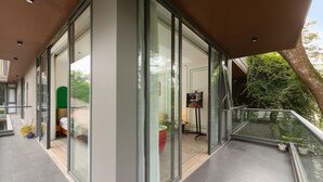 Een moderne hotelkamer met grote glazen deuren, een balkon met een hekwerk en uitzicht op het omliggende landschap.