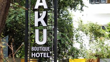 A sign for HAKU Boutique Hotel with a modern design, surrounded by greenery.