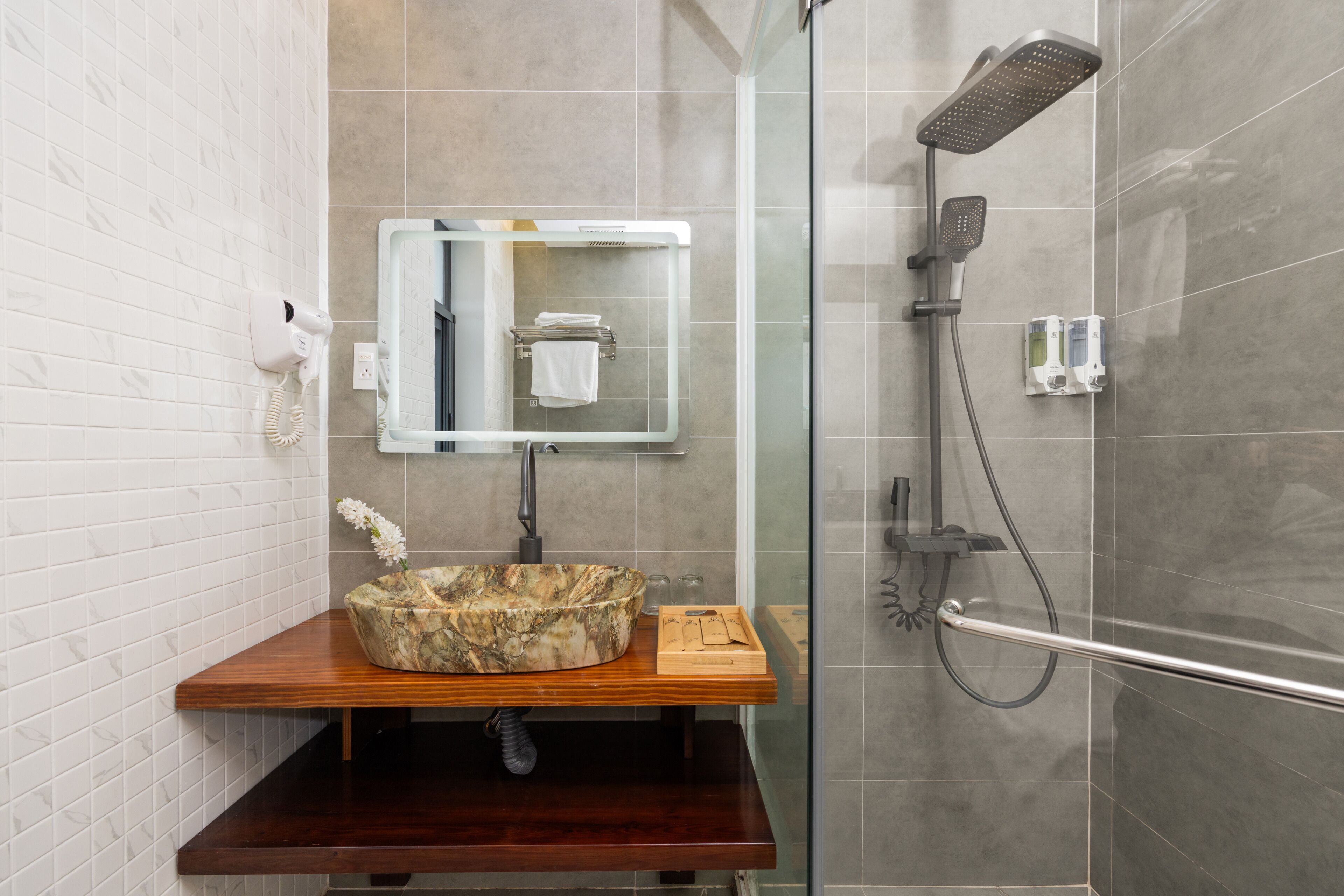A bathroom with a marble sink, a glass shower enclosure, and a towel rack.
