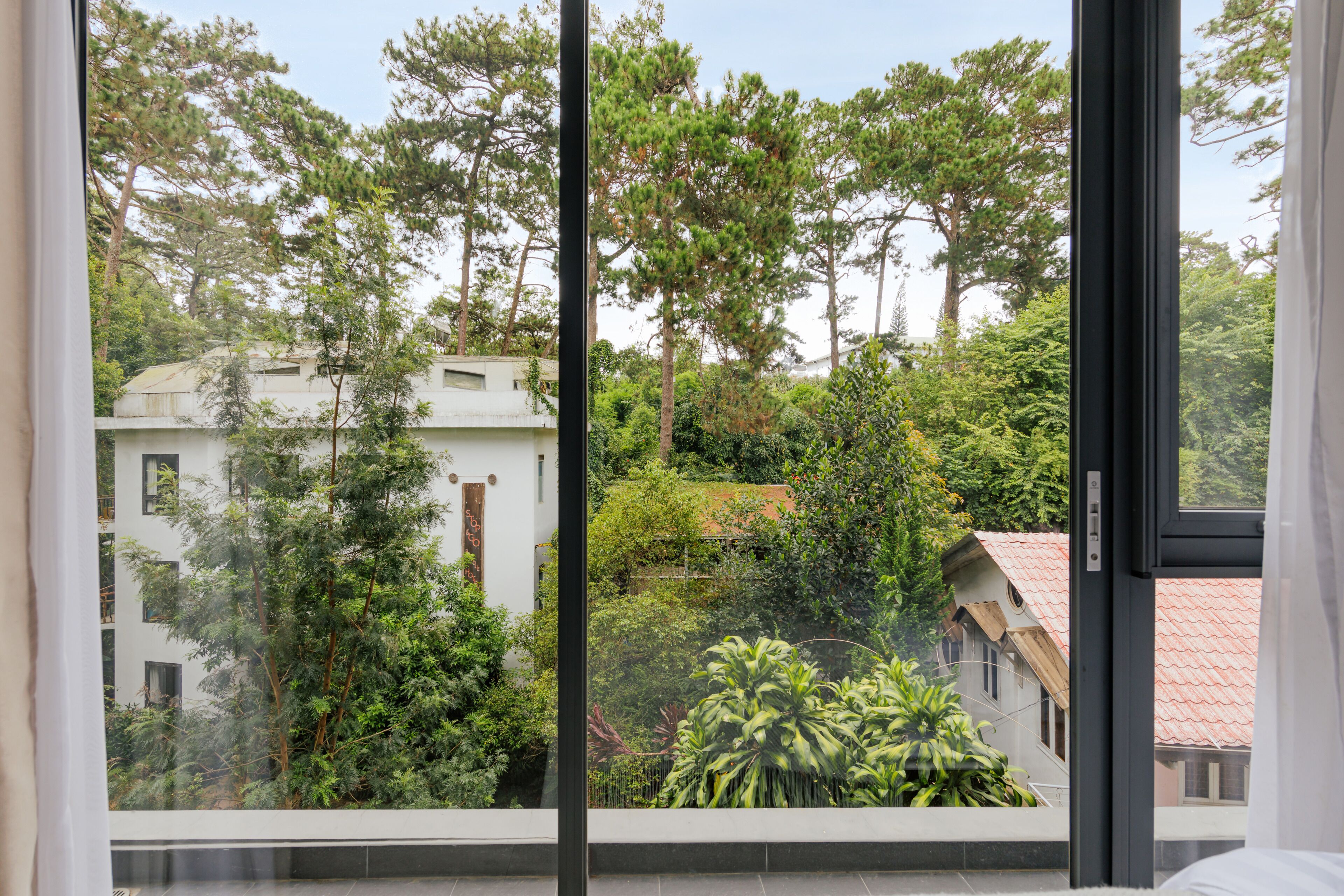 A view from a window with a view of a building surrounded by trees.