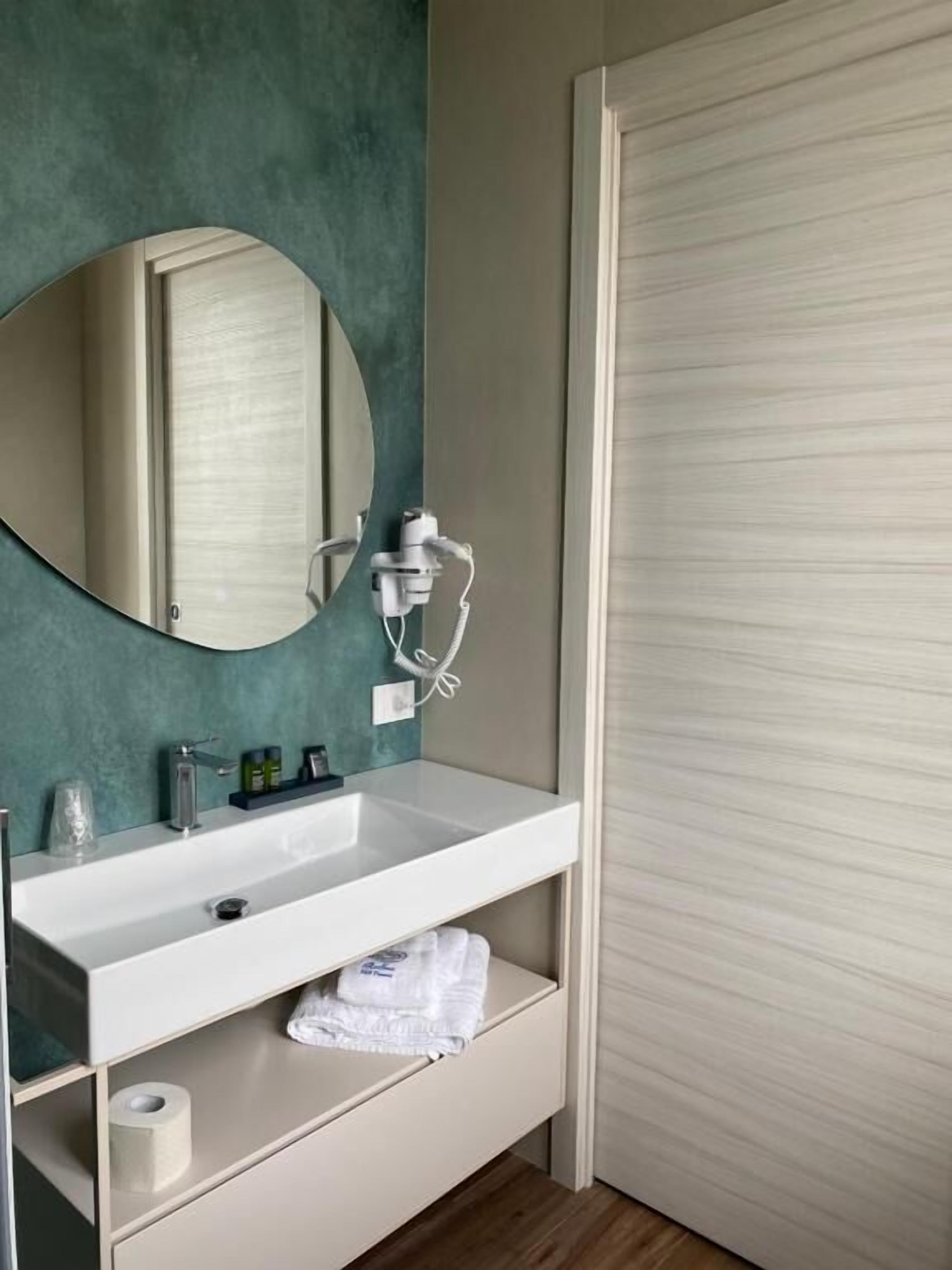 A bathroom with a white sink, mirror, and towel rack.