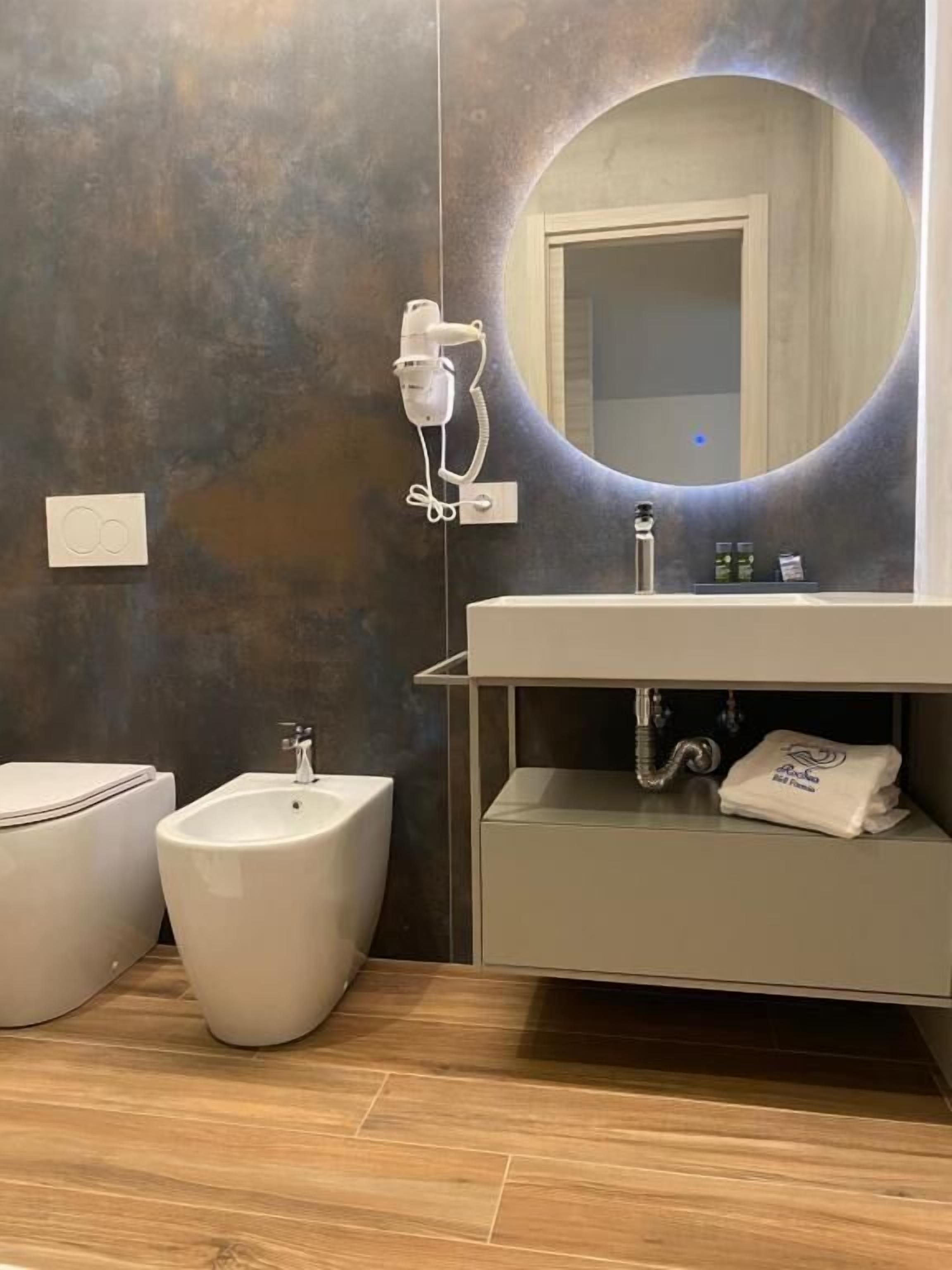 A modern bathroom with a bidet, a sink, a mirror, and a towel rack.