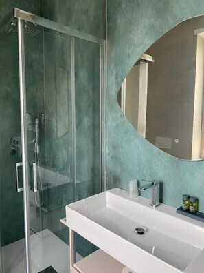 A modern bathroom with a glass shower enclosure, a white sink, and a large mirror.