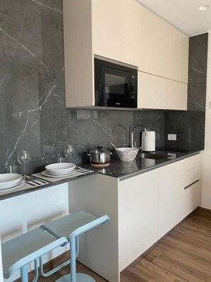 A modern kitchen with a built-in microwave, a sink, and a bar stool.