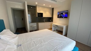 A modern hotel room with a bed, a desk, a TV, and a kitchenette. - RoSea B&B (Formia)