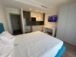 Una habitación de hotel moderna con cama, escritorio, televisión y kitchenette.