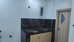 Uma cozinha com bancada preta, armários de madeira, uma pia e uma porta.