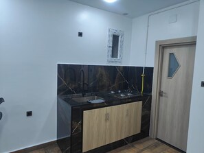 Eine Küche mit schwarzer Arbeitsplatte, Holzschränken, einem Spülbecken und einer Tür.